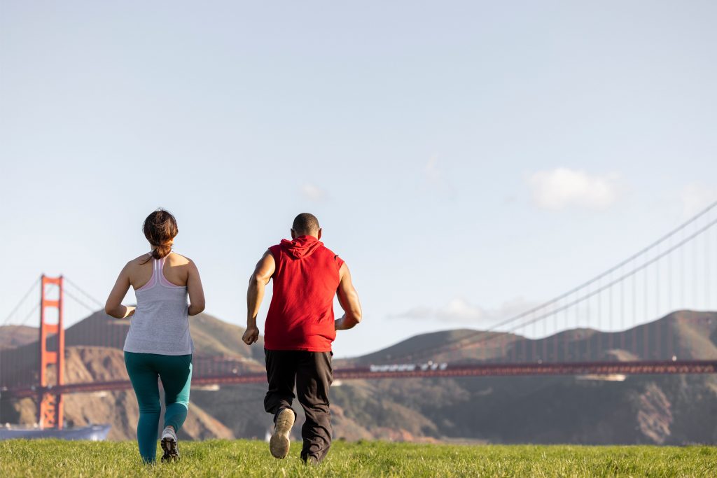 man and woman jogging with the golden gate bridge in the background